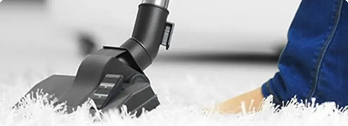 Close-up of a professional vacuuming a white carpet in Wrenshall.